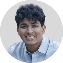 SathvikP220 Hippocratic AI Hippocratic AI Portrait of a smiling young man with dark curly hair wearing a light blue button down shirt against a light gray circular background