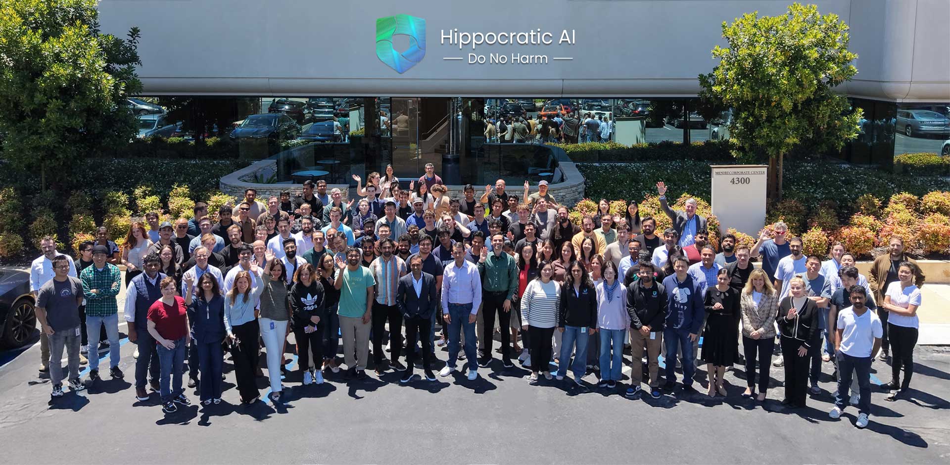 Group of diverse people posing outside a modern building with Hippocratic AI logo and Do No Harm tagline